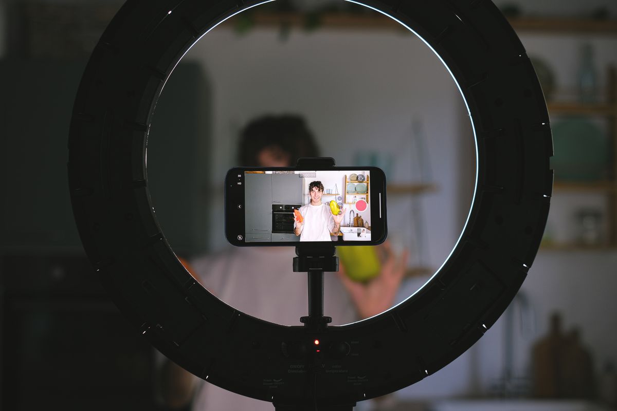 A food creator filming a recipe with a phone and ring light